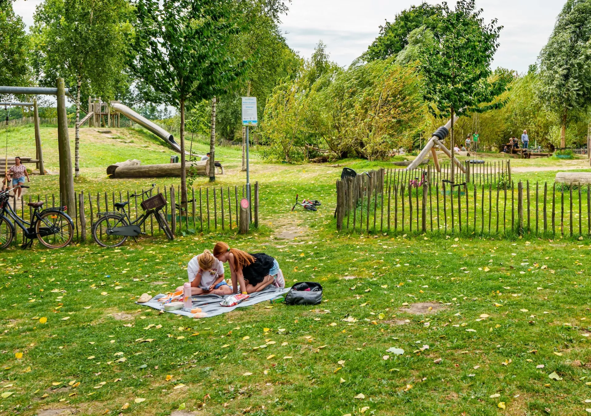 Twee mensen ontspannen op een kleedje in een park.