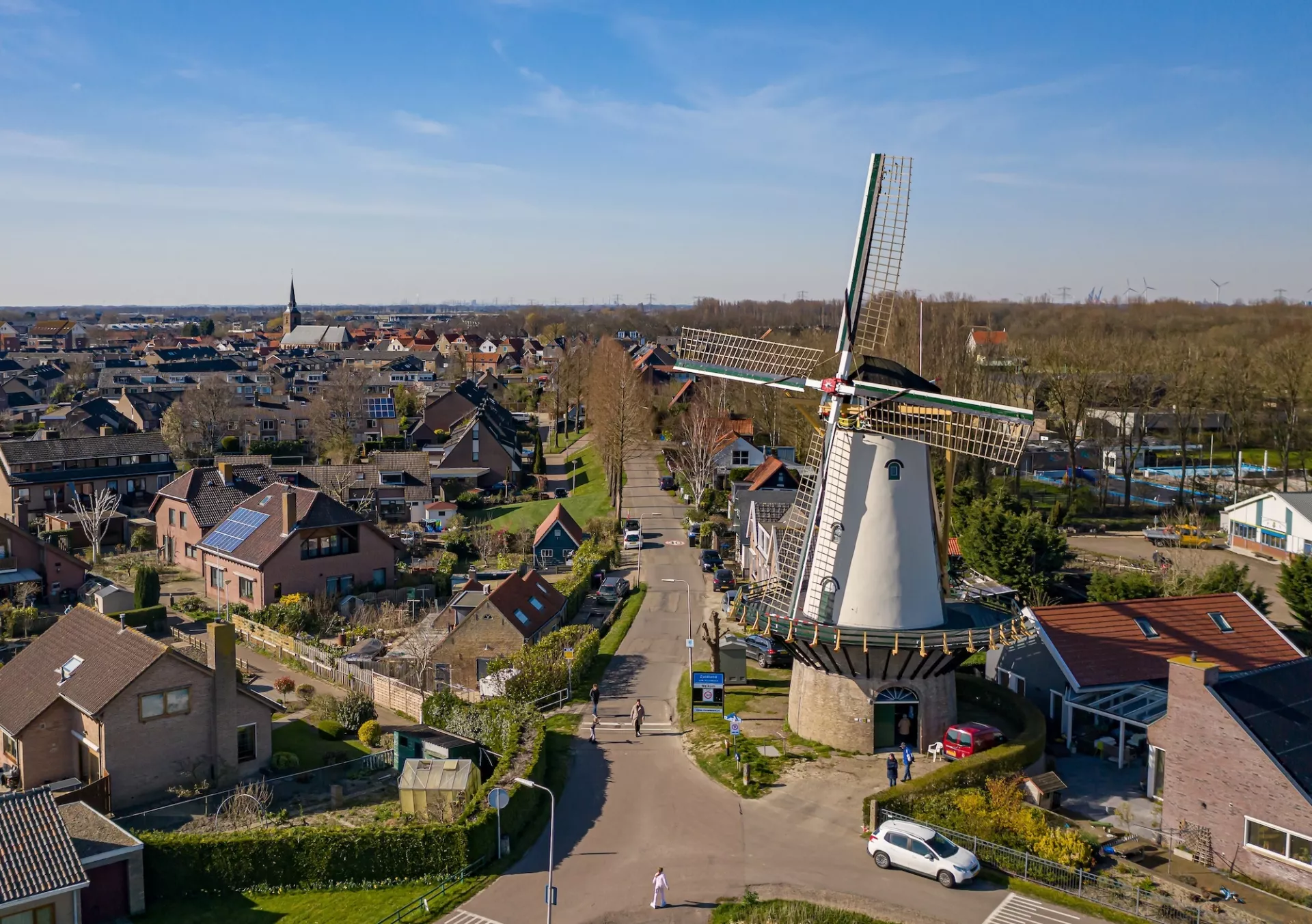 Landschap met witte traditionele Nederlandse molen en omliggende huizen.