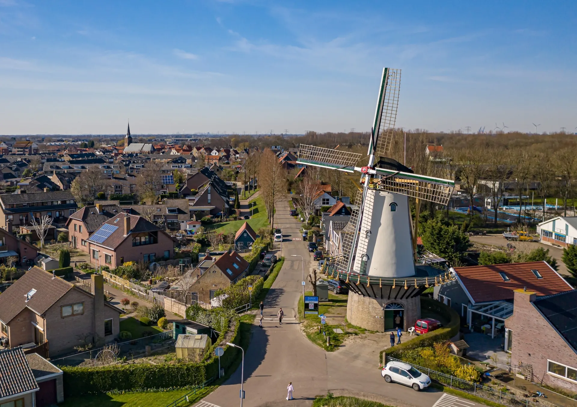 Landschap met witte traditionele Nederlandse molen en omliggende huizen.