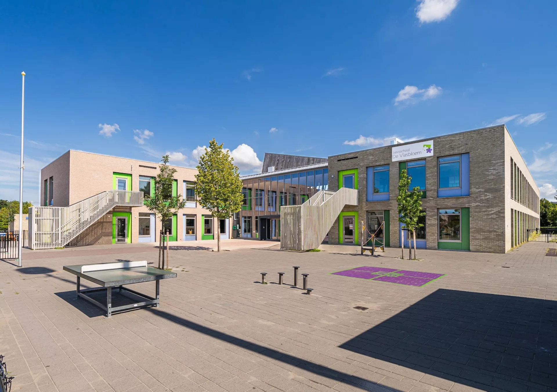 Modern schoolgebouw met speelplaats en kleurrijke ramen.