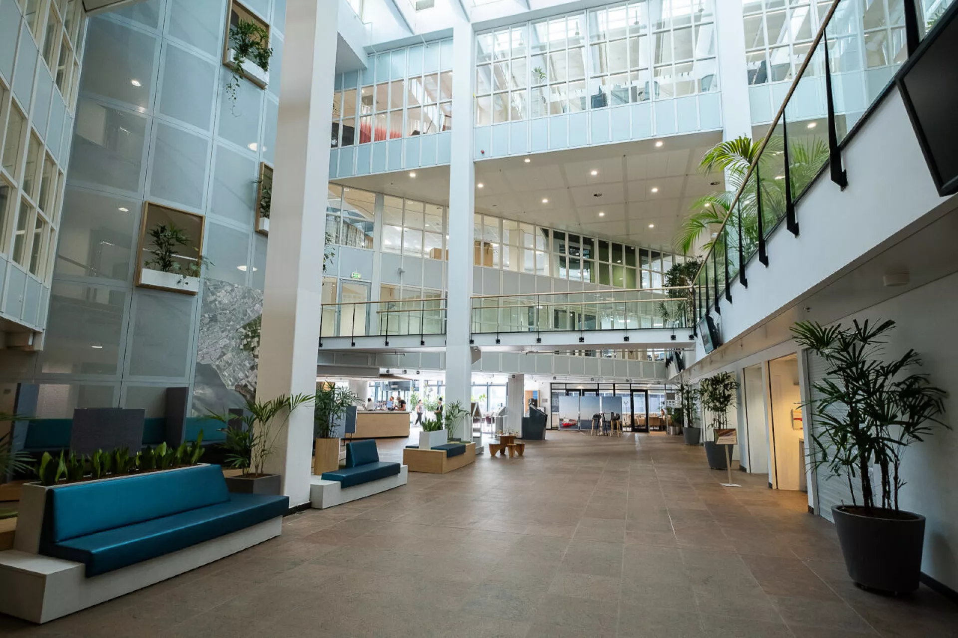 Ruime, moderne, lichte lobby met glazen wanden en groene planten.