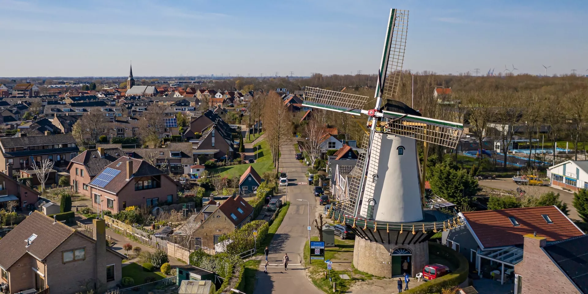 Landschap met witte traditionele Nederlandse molen en omliggende huizen.