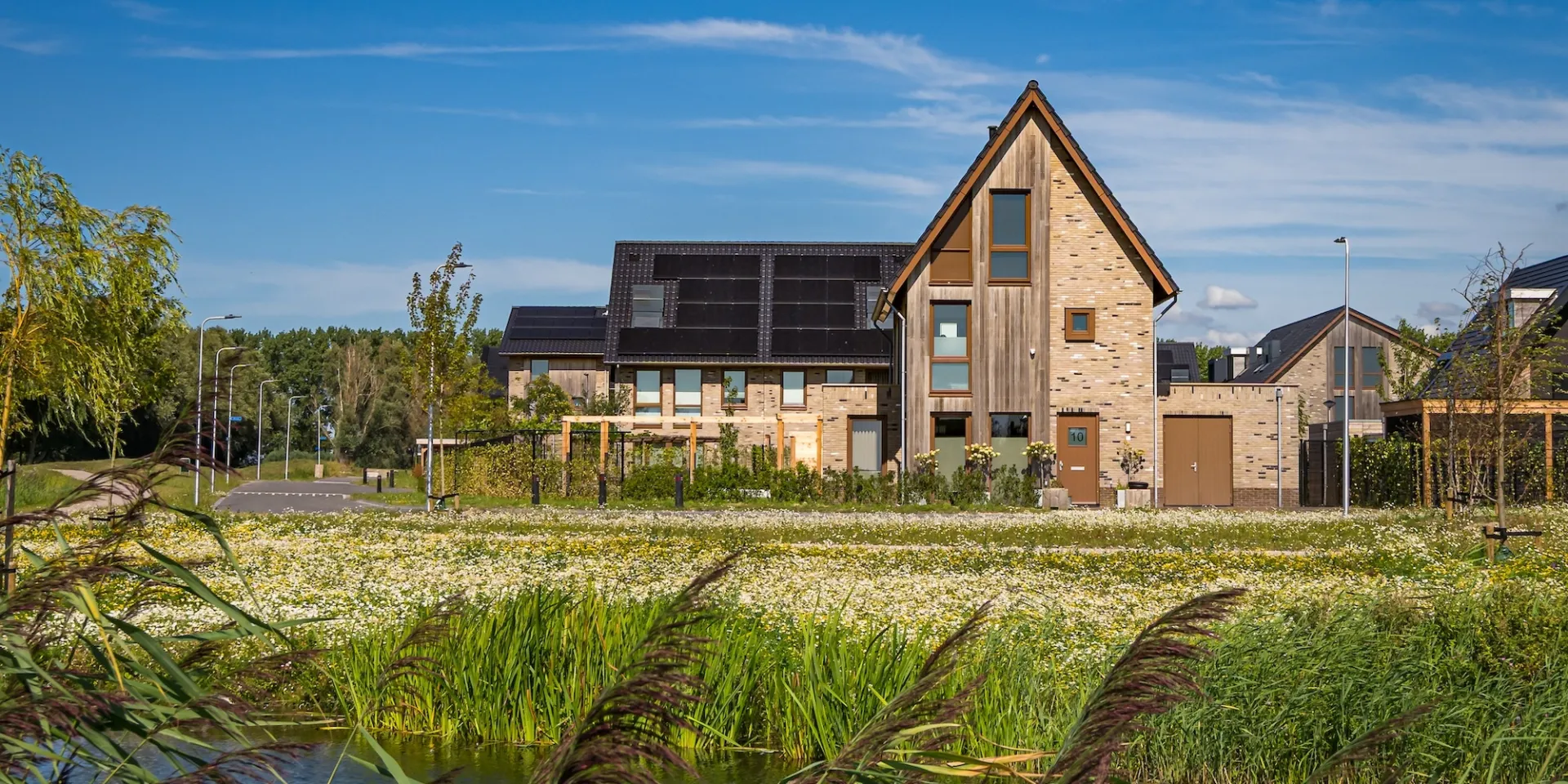 Een modern huis aan het water met een groene omgeving.